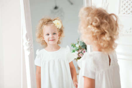 Little pretty girl in white dress playing in homeの写真素材