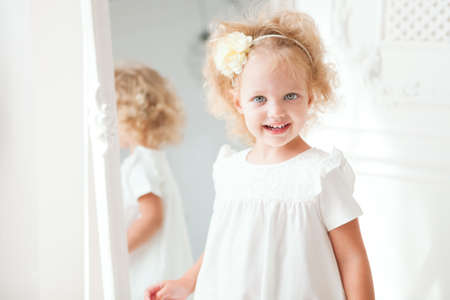 Little pretty girl in white dress playing in homeの写真素材