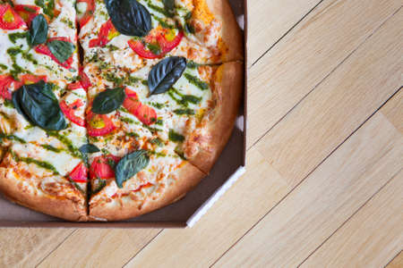 Hot tasty italian pizza with vegetables in box on wooden background.の写真素材