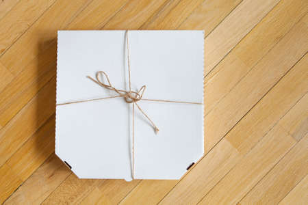 Close up of a white pizza box template on wood background.の写真素材