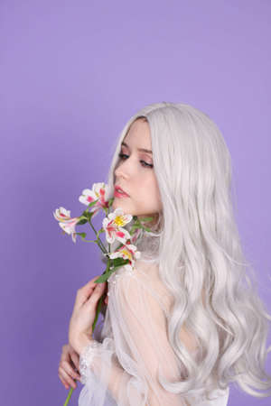 blonde skinny girl in a white transparent dress on a purple backgroundの写真素材