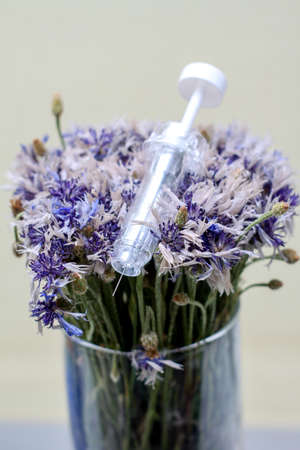 syringe in flowers. Cosmetological procedures. Injections, injections. Diseases, treatment, medicine, vaccine.の写真素材
