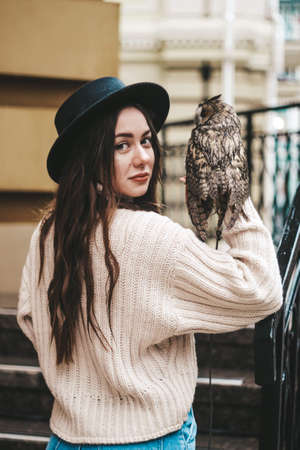 cute tender girl holding an owl on her hand.