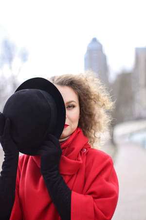 a very sad curly-haired girl in a bright raincoat with emotions on her face.の写真素材