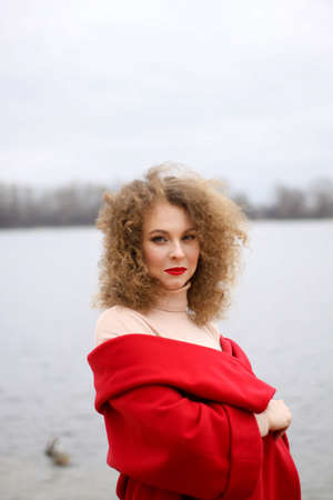 a very sad curly-haired girl in a bright raincoat with emotions on her face.の写真素材