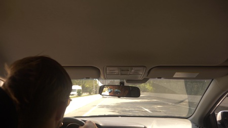 a young handsome man in sunglasses leads a car at high speed, along a highway with a view of the...