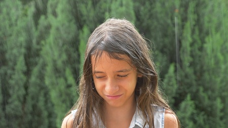 Young sad girl brunette with long hair standing in pouring rain without umbrella. close-upの写真素材