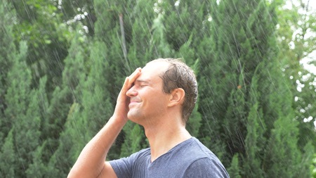 A young handsome guy in the rain. drops of water fall on his face. close-up
