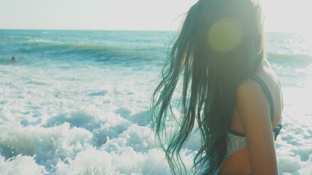 beautiful brunette girl with long blue hair, developing in the wind, against a background of sea waves during a storm. freedom, creativity, mystery.の写真素材