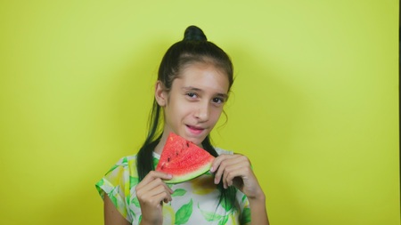 lovely cheerful girl eating a watermelon, on a yellow background.の写真素材