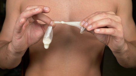 close-up. men's hands hold the used tied condom. The concept of safe sex and contraceptionの写真素材