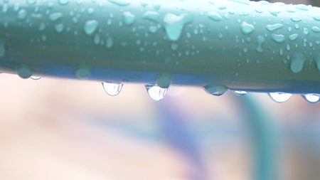 Drops of water hang on the wet iron blue railing, after the rain. Nature. Cloudy weather. rainy, close-up.の写真素材