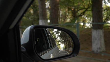 View out the rearview mirror, when the car passes along the road in the summer.