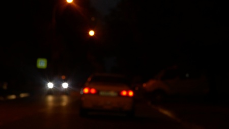 Driving at night. View the windshield and blurred cars in the city. window of the front car with a...