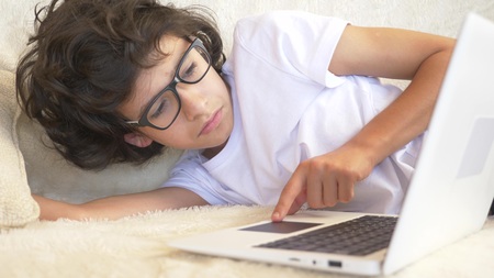 cute boy teenager wearing glasses sleeps on couch next to laptop.の写真素材