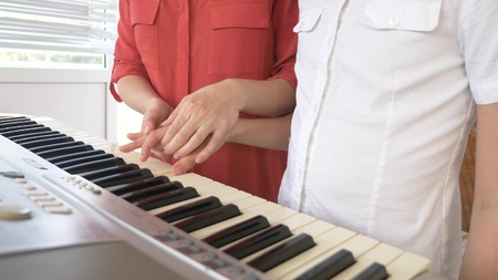 close-up. a piano teacher teaches a child to play the piano, setting the hands.の写真素材