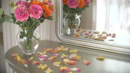Bouquet of multi-colored roses in a transparent round glass vase is on the table with a mirror.の写真素材