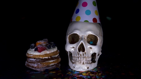 cake and skull in a festive cap on a black backgroundの写真素材