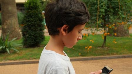 Young teenager with smartphone walking in city, slow motion . the boy walks on the street and looks into his phoneの写真素材
