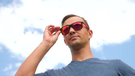 Close-up portrait of a man standing by the wind against the sky with clouds.の写真素材