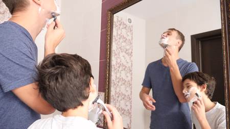 Father and son in the bathroom in the morning, little boy copies his father shaving.の写真素材