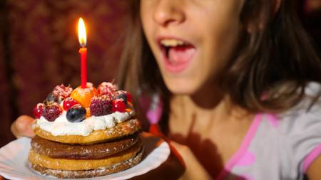 Birthday of the little girl she blows out candles on cake.の写真素材