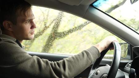 view of the road from the windshield of the car in the rain. Drops of water fall on the glass,...