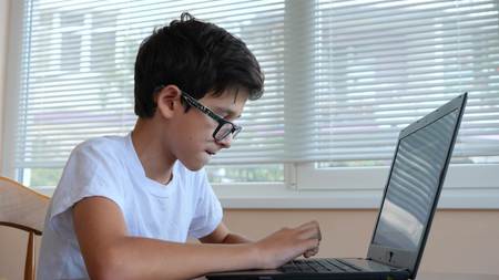 boy teenager uses laptop at home. communication in social networks, training. copy space