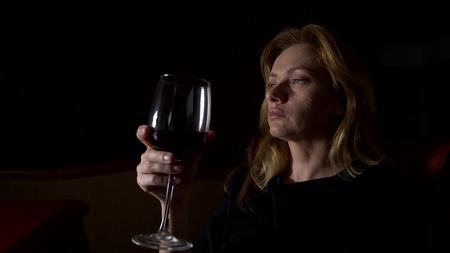 Sad, beautiful woman drinking wine at night. close-up,の写真素材