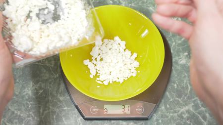 someone measures cottage cheese in electronic form in the kitchen. pour the croup into a deep round bowl, standing on a flat weighing platformの写真素材