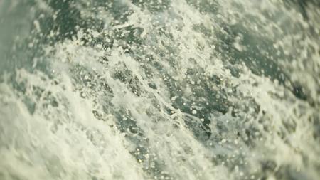 engine propellers churn the water in waves and wakes. The spray of water from the ship's propellers...