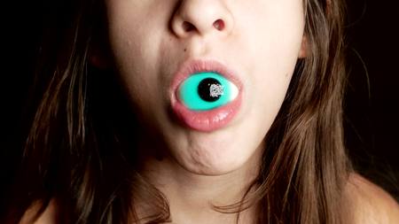 close-up. a cheerful teenage girl takes in the mouth large round candy, similar to the eyes.の写真素材