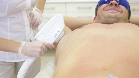male laser hair removal. a doctor in white gloves removes hair from the abdomen and breasts of a man. close-up.の写真素材