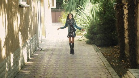 A young girl jumping on a jumping rope in the backyard. Autumnの写真素材