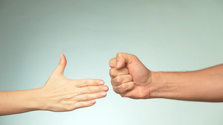 two hands on a blue background. Young man and woman are playing rock paper scissors.の写真素材