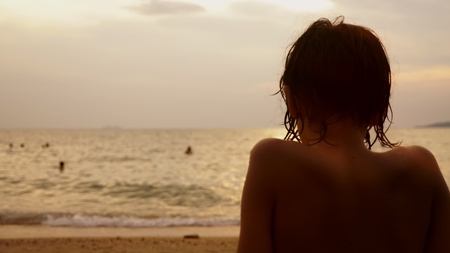 silhouettes, teenager boy with curly hair looks into the sea against the backdrop of the sea landscape, red dramatic sunset, in the sea the sun paints the sea in red.の写真素材
