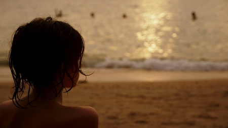 silhouettes, teenager boy with curly hair looks into the sea against the backdrop of the sea landscape, red dramatic sunset, in the sea the sun paints the sea in red.の写真素材