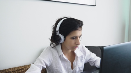 Teenager plays video games. Computer teenager boy with headphones looking at laptop screen