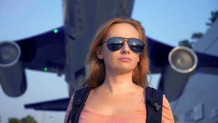 The concept of tourism. Woman tourist in sunglasses with a backpack on her back goes to the airport...