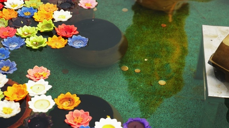 multicolored aroma candles in the form of a lotus flower in a bowl with water for offerings to the...