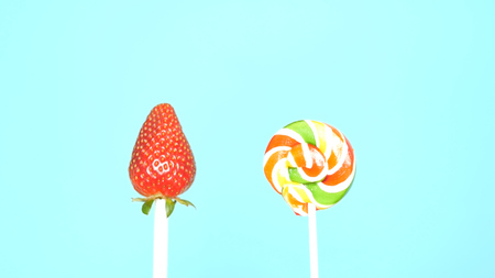 Concept of healthy and unhealthy food. strawberry against candy on a bright blue backgroundの写真素材