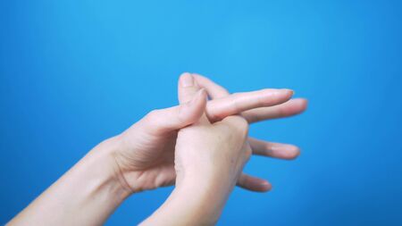 Gentle female hands with natural manicure move beautifully on a blue background. Place for text.の写真素材