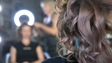 close-up. Professional hairdresser using curling iron. Hair curls in salon,の写真素材