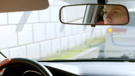 beautiful bald woman driving a car in a traffic jam. face reflection in the rearview mirror