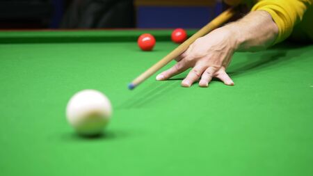 unrecognizable people play billiards. snooker. the pocket is in focus. blurred background.