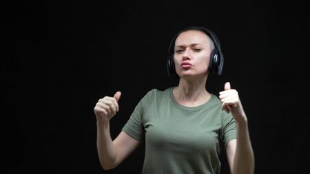 Young bald woman with headphones dancing on a black backgroundの写真素材