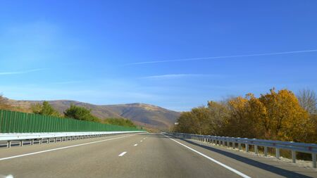 The view from the car on a hilly road, along magnificent mountains covered with bright colorful...