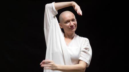 beautiful bald woman in white clothes is dancing on a black backgroundの写真素材