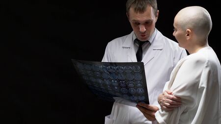 concept Oncological patient, bald woman and doctor man are viewing tomography results on black...