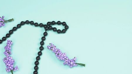 necklace of black agate and artificial lavender flowers on blue backgroundの写真素材